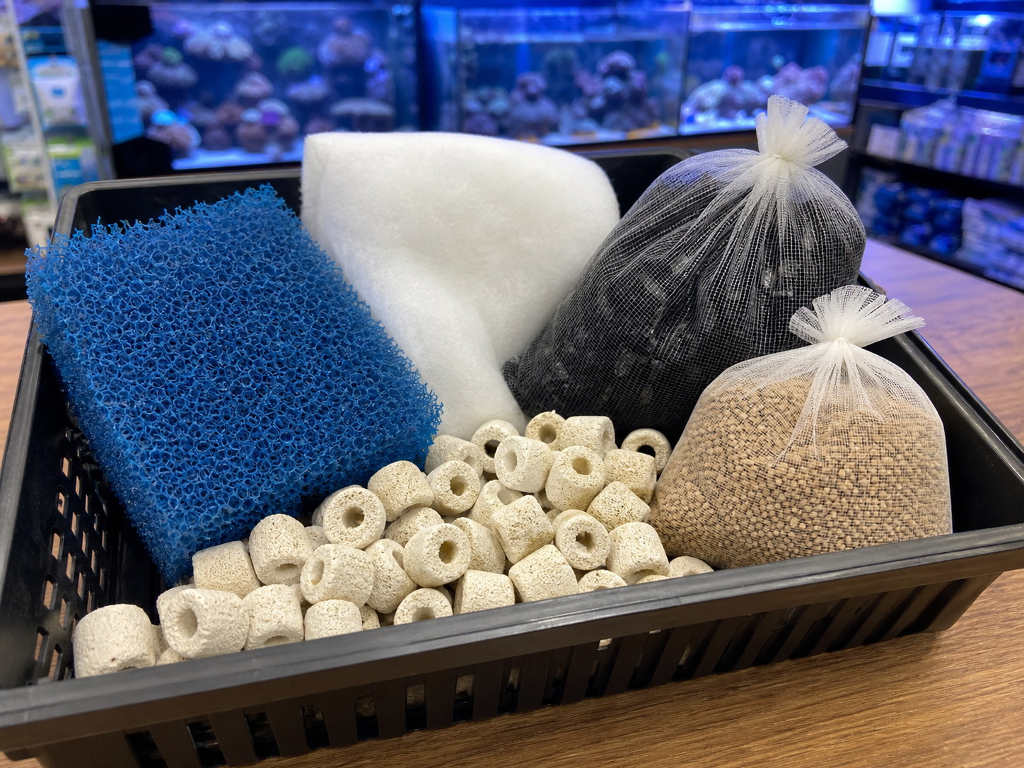Aquarium filter media in a basket with sponge, floss, ceramic rings, carbon, and specialty media bags